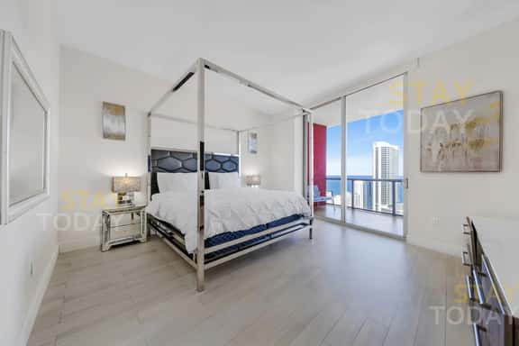 This master bedroom features a sleek king bed and a private bathroom. Spacious and modern, it boasts large glass doors with direct balcony access, filling the room with light and offering breathtaking ocean views right from your bedside.