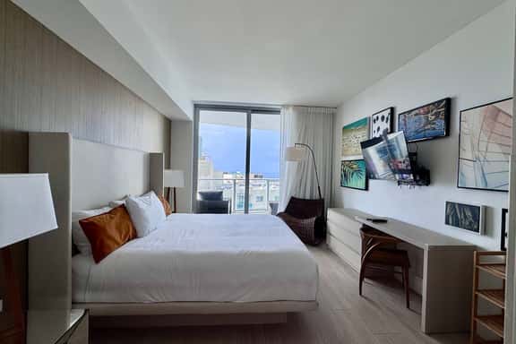 Step into a serene retreat with a plush king bed, modern décor, and floor-to-ceiling windows opening to a private balcony with city and ocean views. The en-suite bathroom also connects to the living room for added convenience.