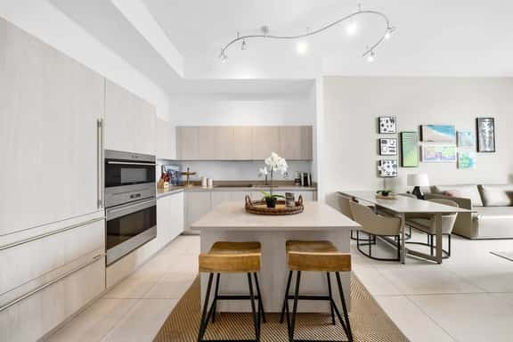 This kitchen features a spacious island with seating for two, modern appliances, and ample counter space - perfect for cooking meals or enjoying a casual breakfast in a bright, open setting.