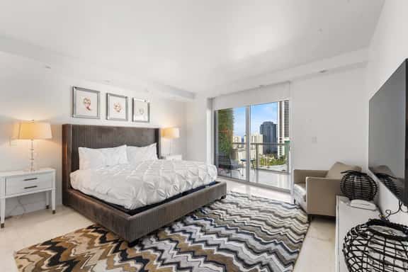 Step into the spacious master bedroom, featuring a king-size bed, en-suite bathroom, and direct balcony access through a glass door that fills the room with natural light - a perfect blend of comfort and style for a restful stay.