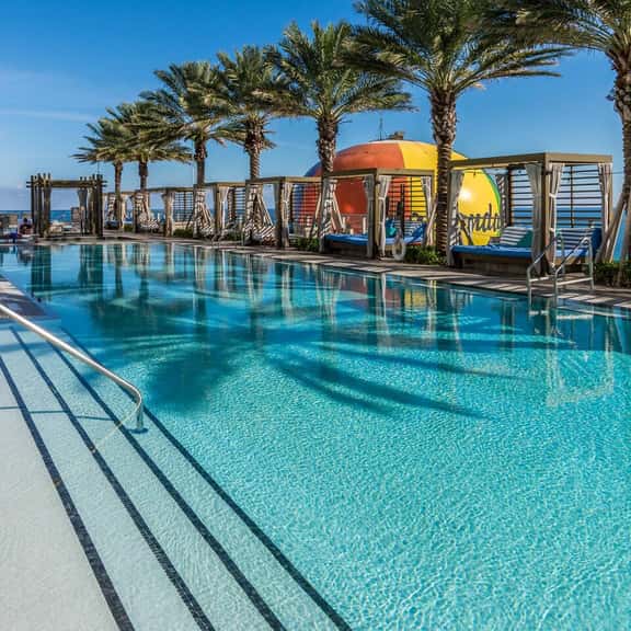 Relax by the spacious outdoor pool surrounded by palm trees and cabanas. Enjoy the peaceful atmosphere and comfortable loungers while soaking up the Miami sun. Perfect for a refreshing swim or quiet relaxation.